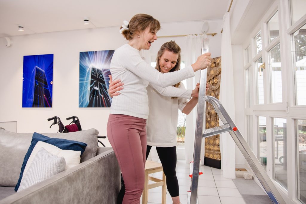 Therapeutin unterstützt Klientin beim Aufstehen im Wohnraum